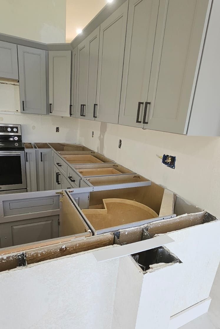 Gray shaker cabinets installed along a kitchen wall, base units standing open with a corner carousel fitted, waiting for countertops.